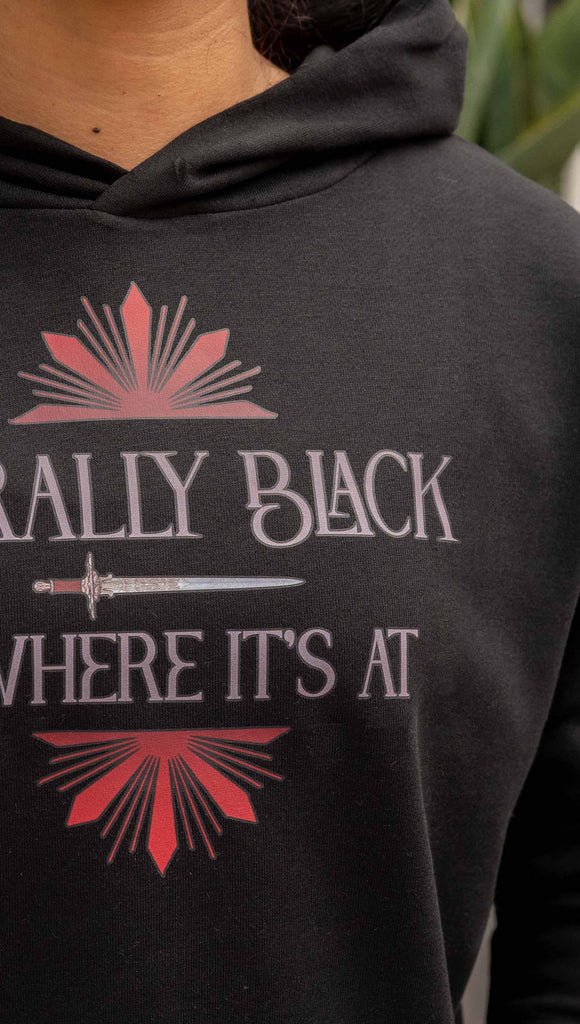 Zoomed in photo of girl wearing lightweight comfy hoodie with the phrase, "Morally Black is Where it's At" printed on the front with a dagger and bright red starbust details. The hoodie is slightly cropped length and black.