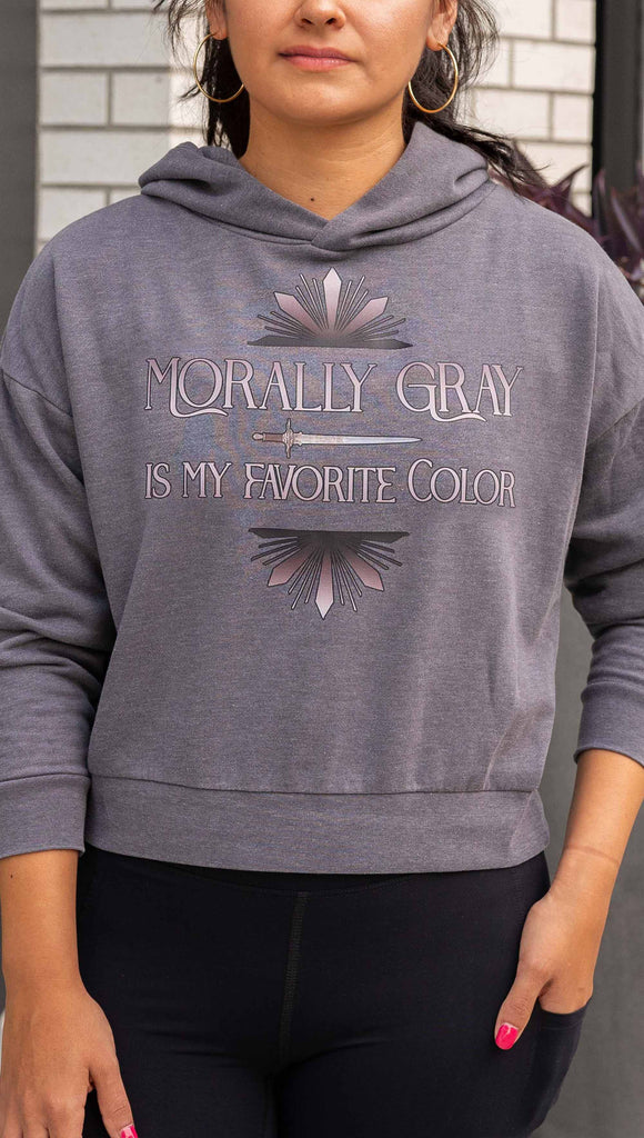 Girl wearing gray hoodie with the phrase, "Morally Gray is my Favorite Color" with a dagger and gray starburst detail printed above/below the text. The hoodie color is gray.