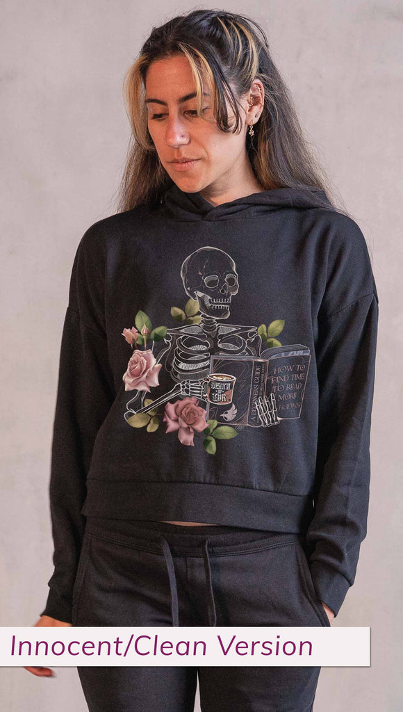 Model wearing WERKSHOP  "Death by TBR" Hoodie in Black Colorway ~ Innocent/Clean version with the phrase, "How to Find Time to Read More Books". Featuring a skeleton holding a book in one hand and a coffee mug in the other with accent roses.