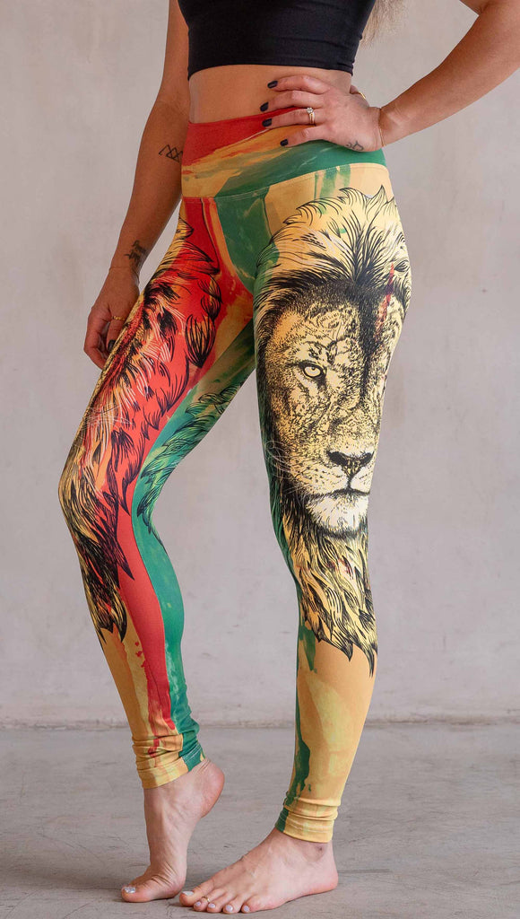 Model wearing WERKSHOP Lion of Zion Athleisure Leggings. The leggings feature a hand illustration of a lion over organic brustrokes in Rastafarian colors.