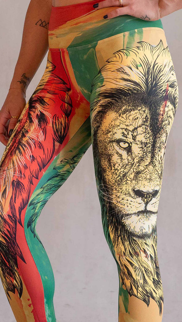 Model wearing WERKSHOP Lion of Zion Athleisure Leggings. The leggings feature a hand illustration of a lion over organic brustrokes in Rastafarian colors.