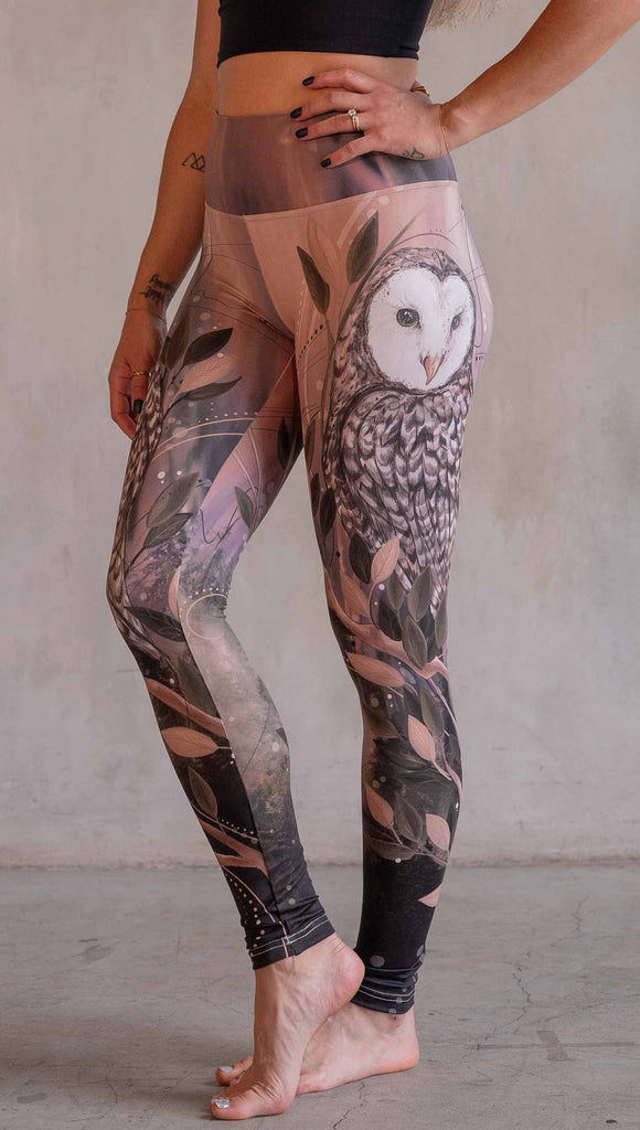 Model wearing WERKSHOP Owls Athleisure Leggings. The leggings are printed with a whimsical barn owl on the thigh surrounded by swirls and leaves on a mauve and cream toned background.
