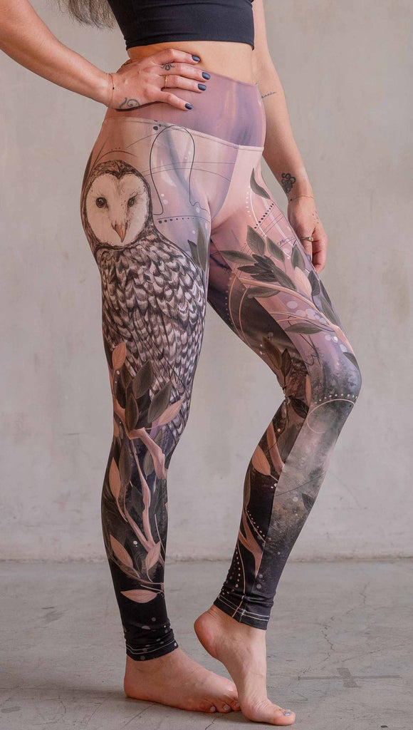 Model wearing WERKSHOP Owls Athleisure Leggings. The leggings are printed with a whimsical barn owl on the thigh surrounded by swirls and leaves on a mauve and cream toned background.