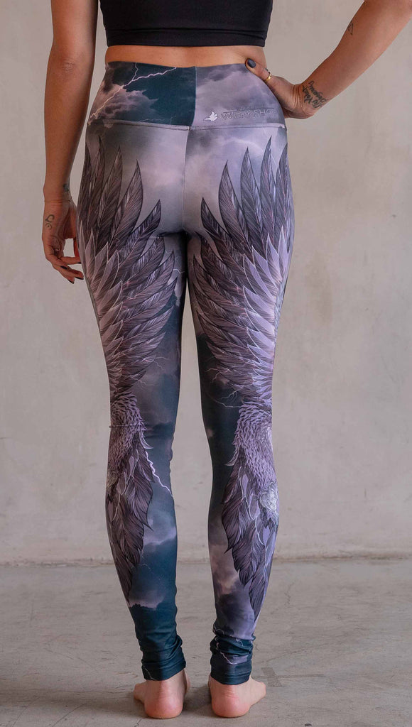 Model wearing WERKSHOP Thunderbird Athleisure Leggings. The artwork printed on the leggings features a thunderbird flying through a stormy sky with lightening. The leggings feature a closed colour pallete with all shades of purple.