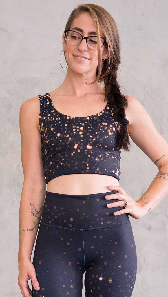 Front view of model wearing gold and silver sparkle WERKSHOP reversible top. With gold bokeh over blue-ish black background on one side and warm silver bokeh on black background on the opposite side.