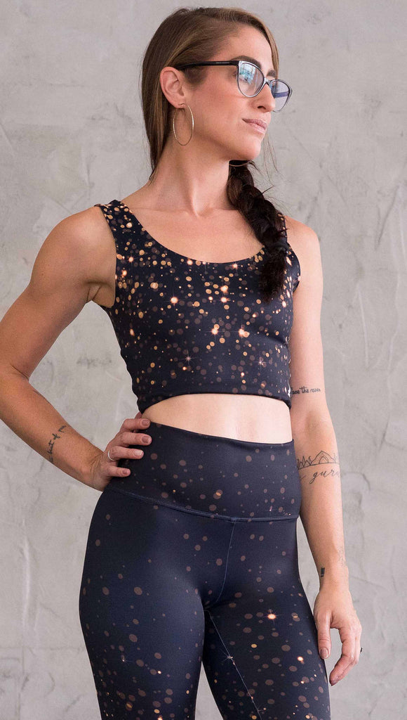 Front view of model wearing gold and silver sparkle WERKSHOP reversible top. With gold bokeh over blue-ish black background on one side and warm silver bokeh on black background on the opposite side.